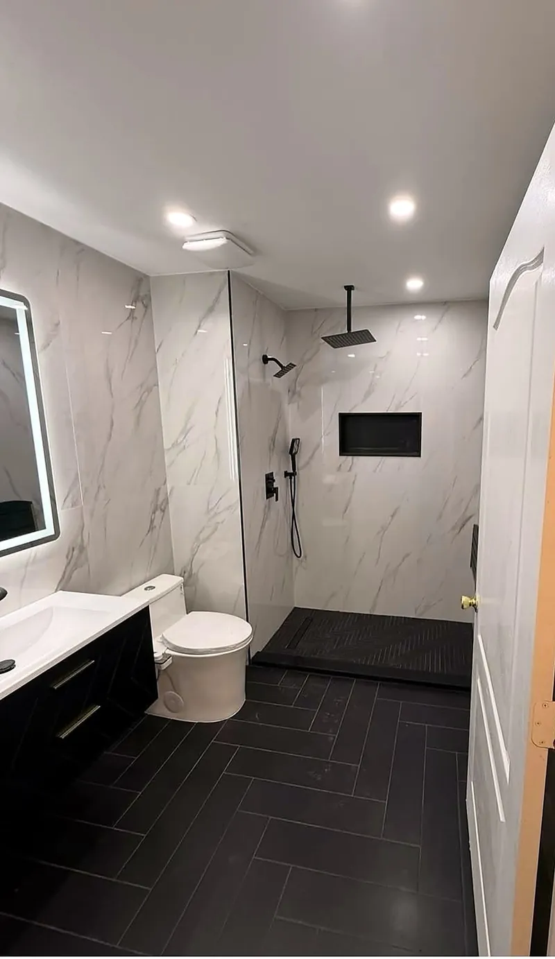 Baño remodelado con piso negro en espiga, ducha de obra y paredes de porcelanato