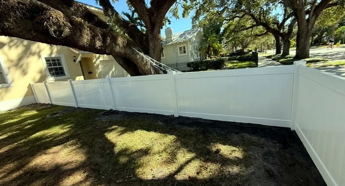 Cerca de vinilo blanca bajo la sombra de un roble